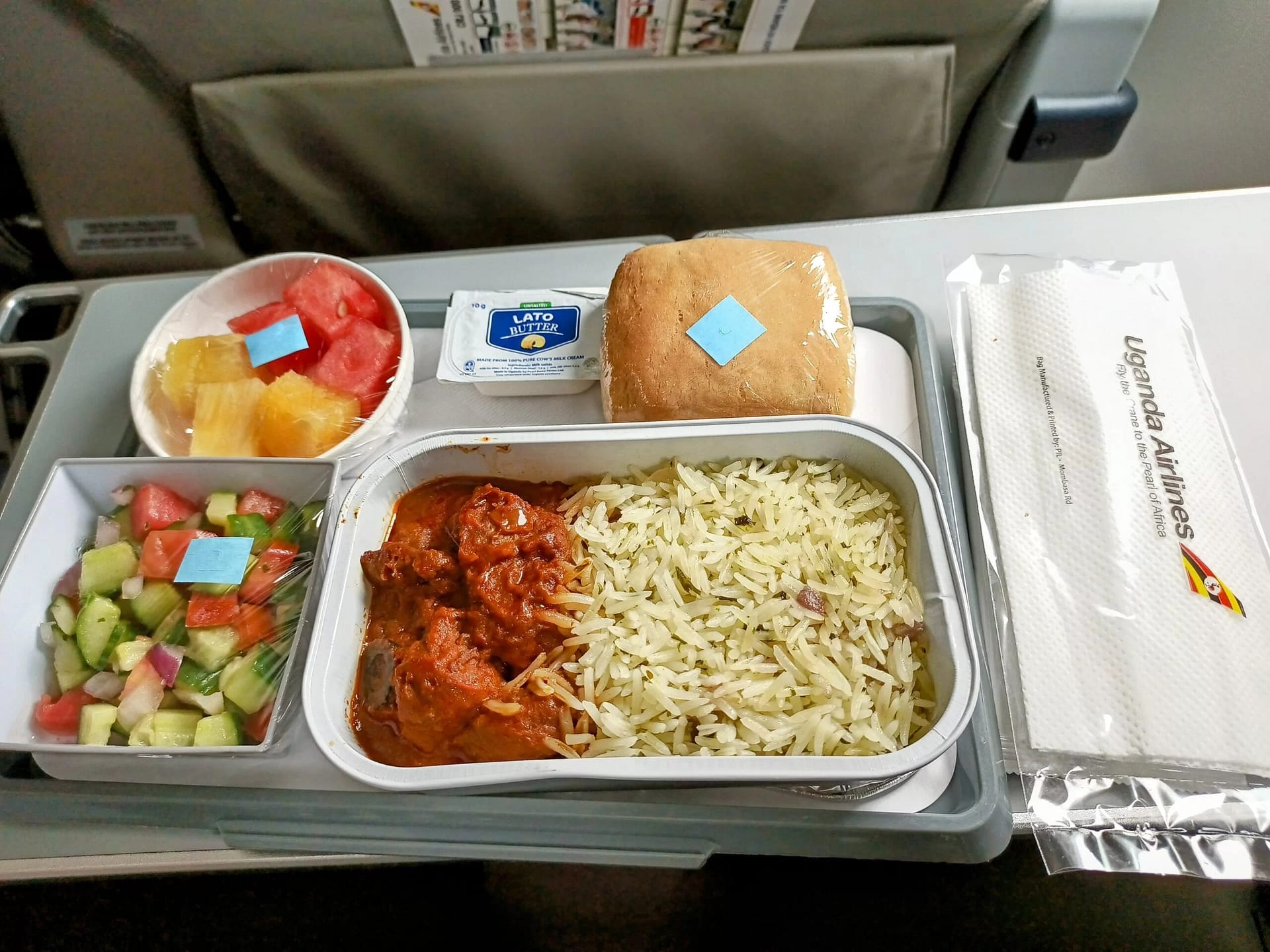 Photo of beef meal option in Uganda Airlines. Bread, butter, fruits, vegetable salad and beef and rice